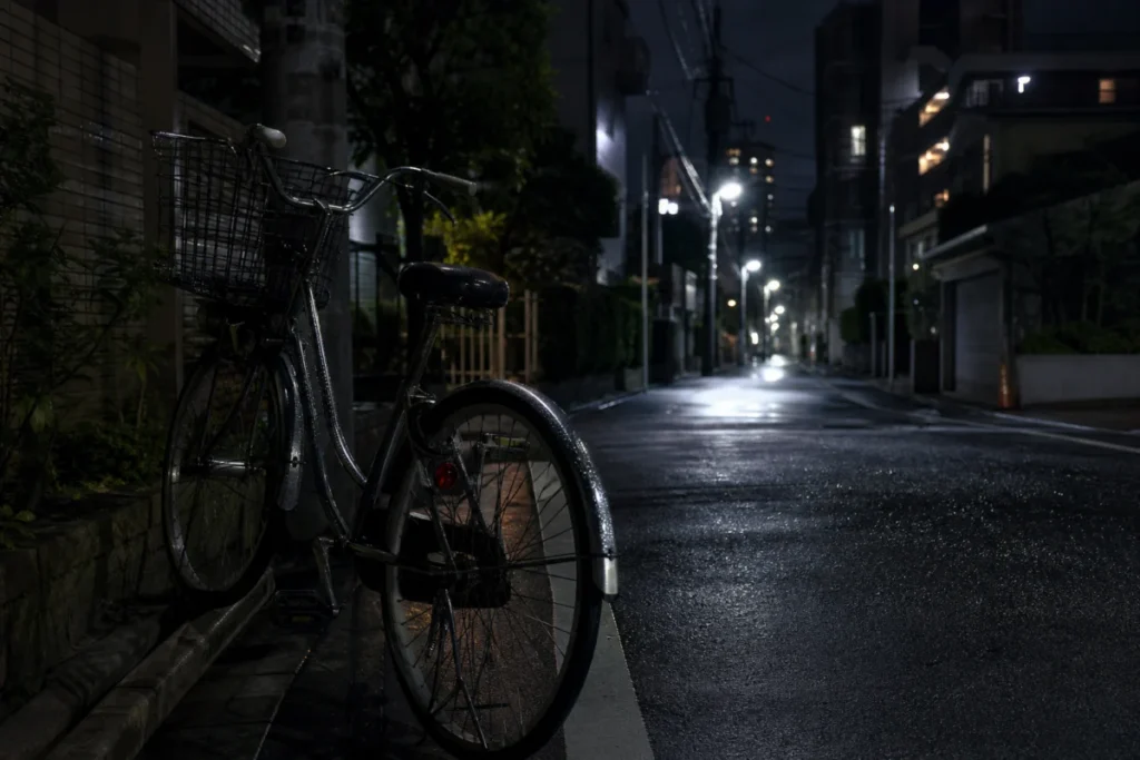 夜の路地に置かれた自転車と街灯の光の筋